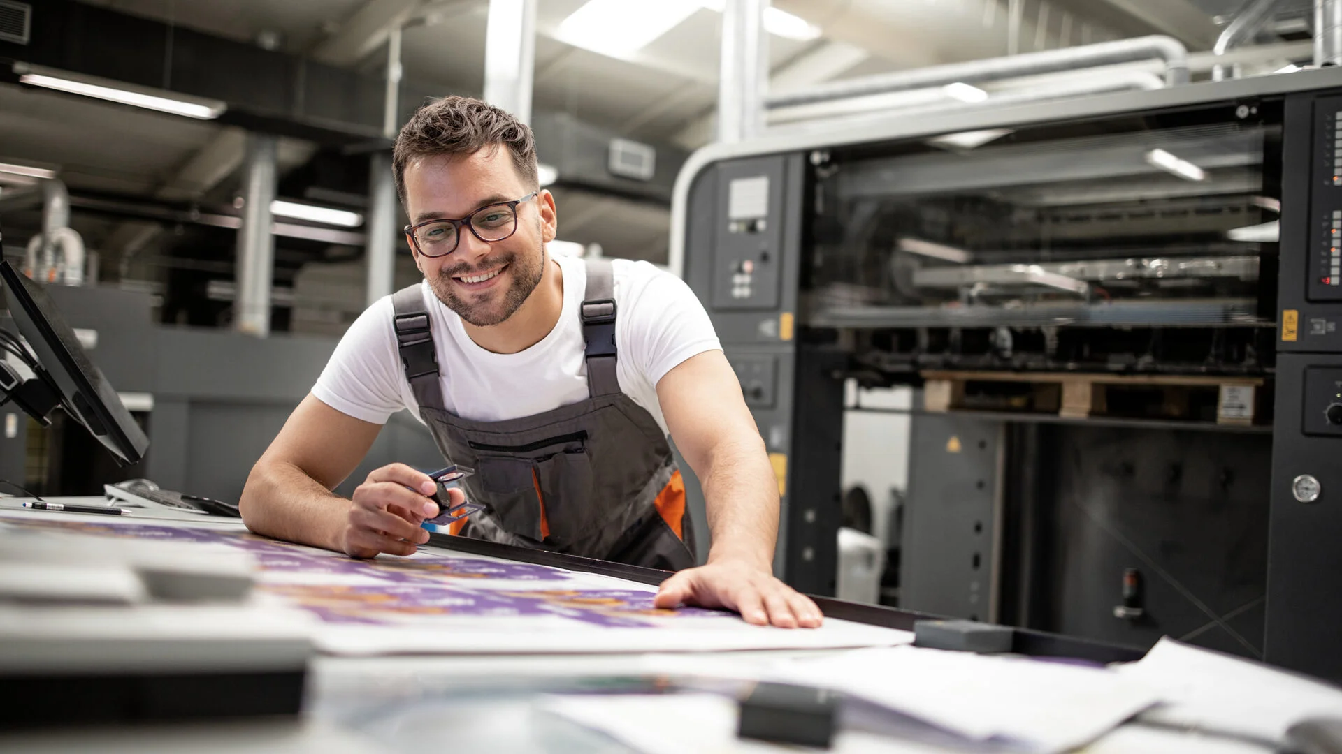 Freundlicher Drucktechniker überprüft die Druckqualität eines Posters in der Druckerei